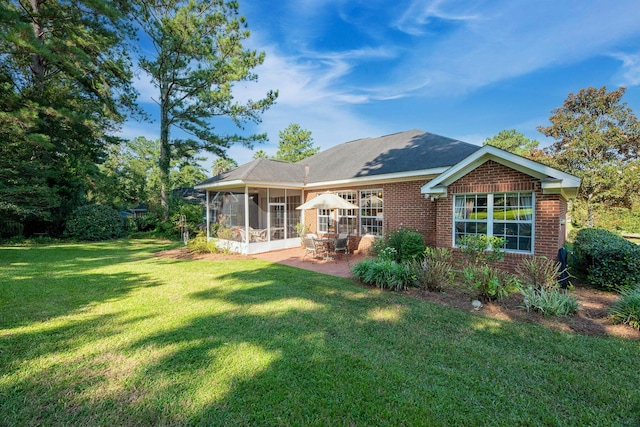 rear view of house with a lawn, a sunroom, and a patio area