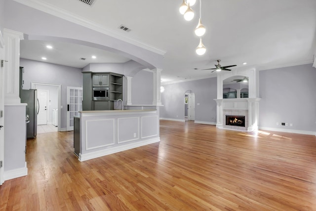 unfurnished living room featuring ceiling fan, crown molding, and sink