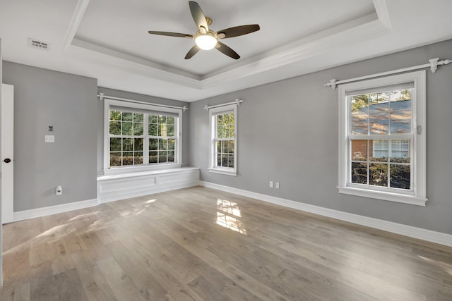 unfurnished room featuring light wood-type flooring, ceiling fan, and a tray ceiling