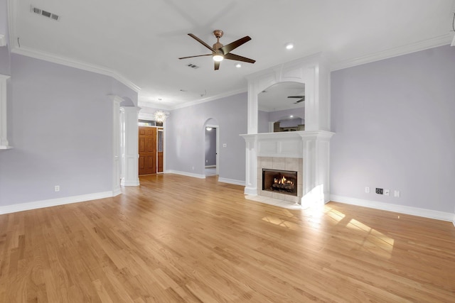 unfurnished living room featuring ceiling fan, light wood-type flooring, a tile fireplace, and crown molding