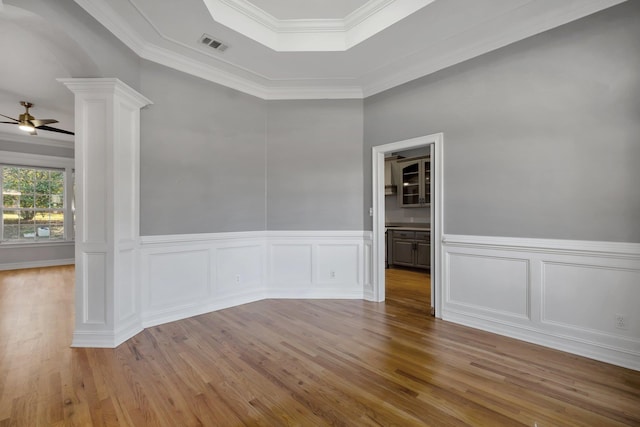 spare room featuring ornamental molding, ceiling fan, light wood-type flooring, and a tray ceiling