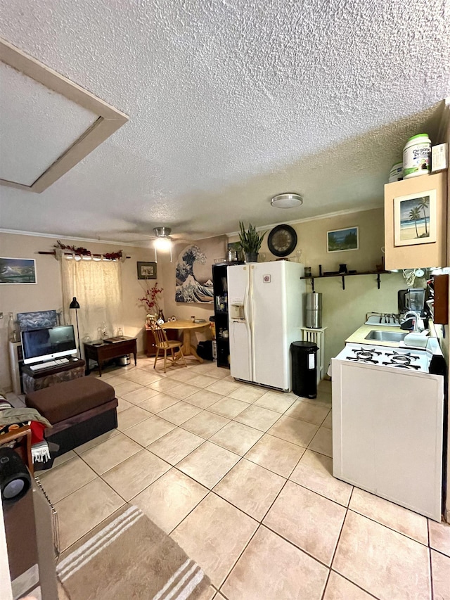 kitchen with a textured ceiling, white appliances, light tile patterned floors, and sink