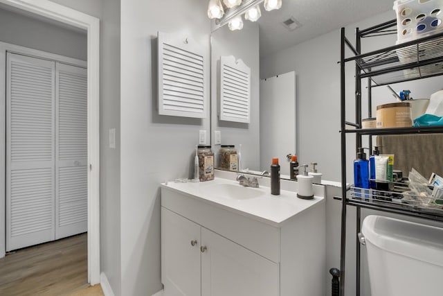 bathroom with a textured ceiling, vanity, hardwood / wood-style flooring, and toilet