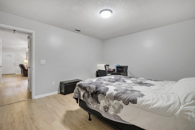 bedroom with light wood-type flooring and a textured ceiling