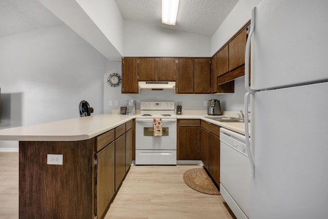 kitchen featuring light hardwood / wood-style floors, kitchen peninsula, a textured ceiling, white appliances, and vaulted ceiling