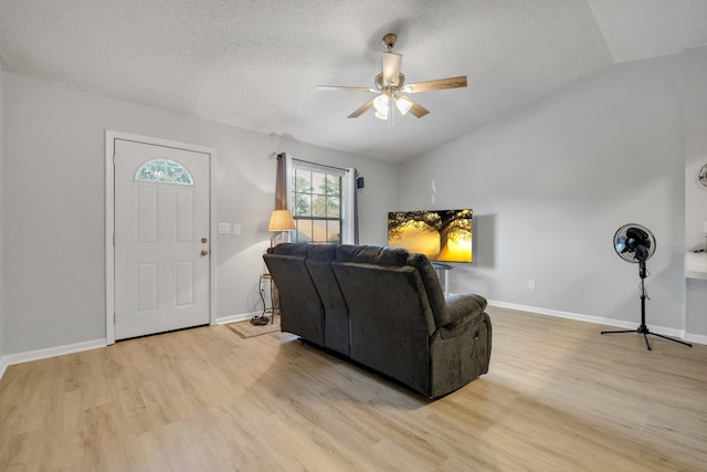 living room featuring ceiling fan, a textured ceiling, light wood-type flooring, and vaulted ceiling