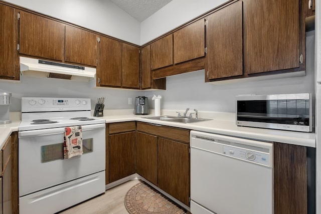 kitchen with white appliances, a textured ceiling, sink, and light hardwood / wood-style flooring