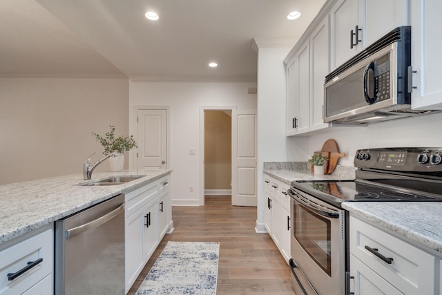 3283 Gramercy Pl, Tallahassee, FL 32308 - kitchen with stainless steel appliances, crown molding, light stone counters, light wood-style floors, and white cabinetry