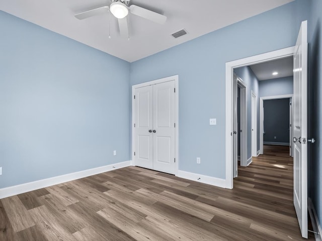 unfurnished bedroom featuring ceiling fan, a closet, and wood-type flooring