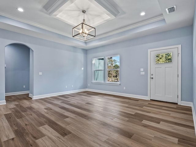 foyer with hardwood / wood-style flooring, an inviting chandelier, a tray ceiling, and ornamental molding