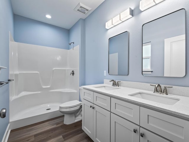 bathroom with hardwood / wood-style floors, vanity, toilet, and walk in shower