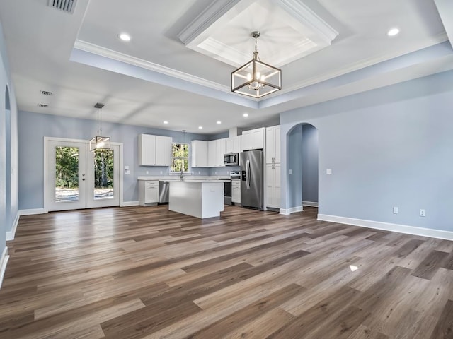 kitchen featuring a center island, stainless steel appliances, hardwood / wood-style floors, decorative light fixtures, and white cabinets