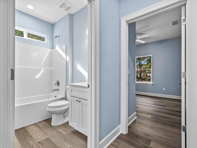 full bathroom featuring hardwood / wood-style floors, vanity, shower / tub combination, ceiling fan, and toilet