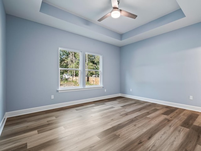 spare room featuring a tray ceiling, ceiling fan, and hardwood / wood-style floors