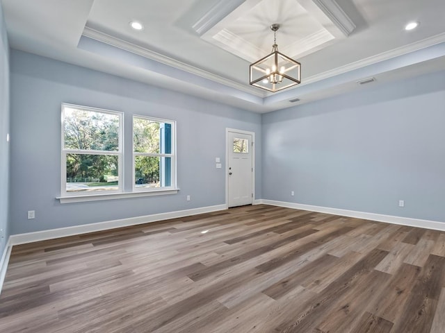 spare room with a chandelier, wood-type flooring, a tray ceiling, and ornamental molding