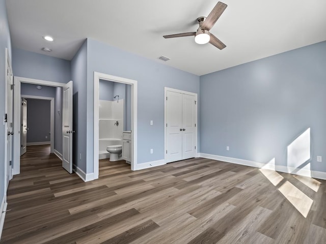 unfurnished bedroom with ensuite bathroom, ceiling fan, and dark wood-type flooring