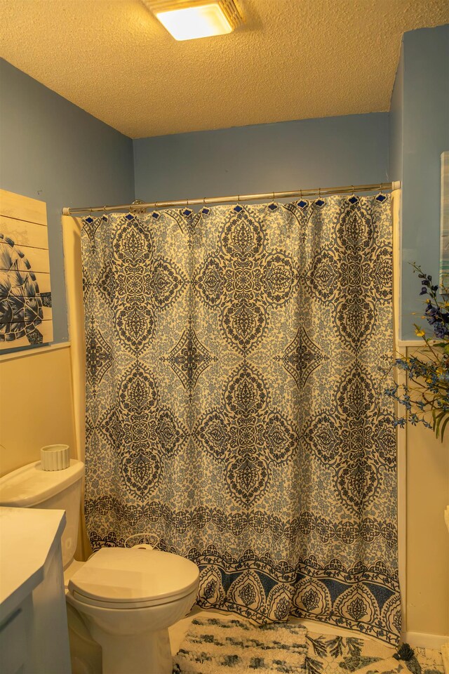 bathroom featuring vanity, walk in shower, a textured ceiling, and toilet