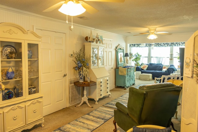 carpeted living room with a textured ceiling, ceiling fan, and crown molding