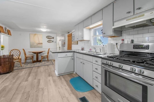 1405 SE 2nd Ave, Steinhatchee, FL 32359 - kitchen with gas stove, under cabinet range hood, light wood-type flooring, backsplash, and a peninsula