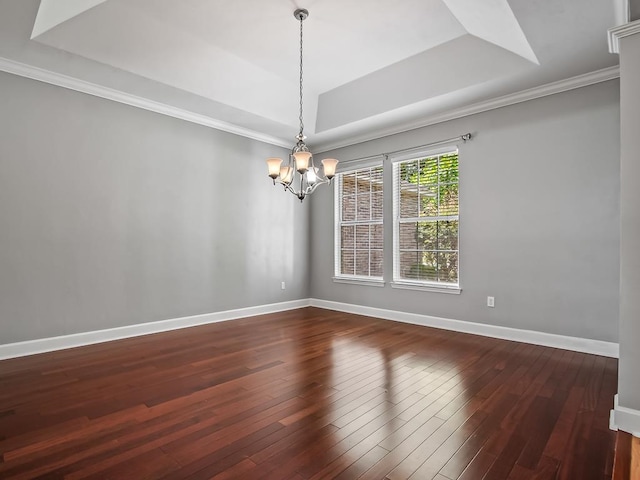 spare room featuring dark hardwood / wood-style floors, ornamental molding, a chandelier, and a tray ceiling