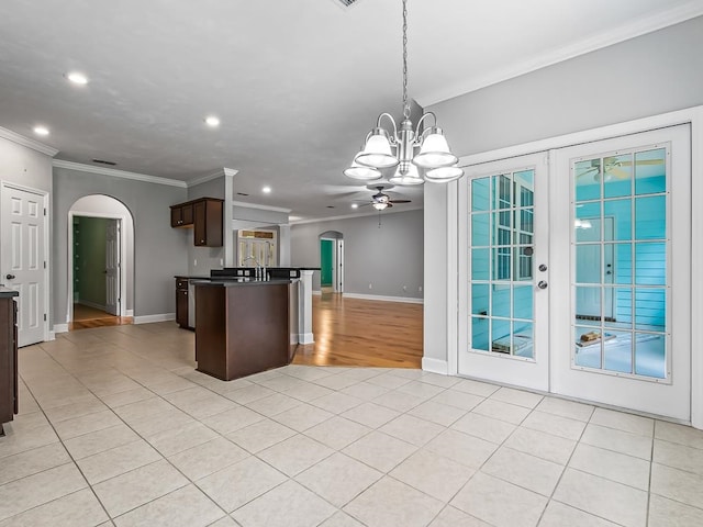 kitchen featuring light tile patterned flooring, ceiling fan with notable chandelier, hanging light fixtures, dark brown cabinets, and crown molding