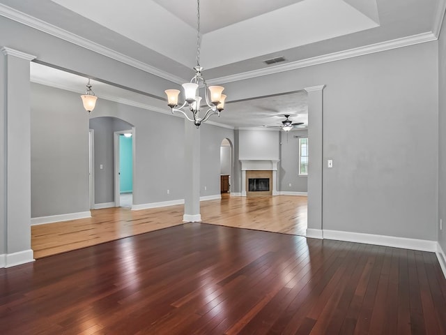 unfurnished living room featuring wood-type flooring, ornamental molding, and ceiling fan with notable chandelier