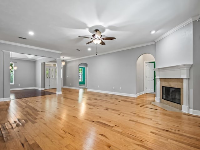 unfurnished living room featuring ornamental molding, light hardwood / wood-style floors, ceiling fan, and a tile fireplace