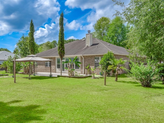 rear view of house with a yard and a gazebo