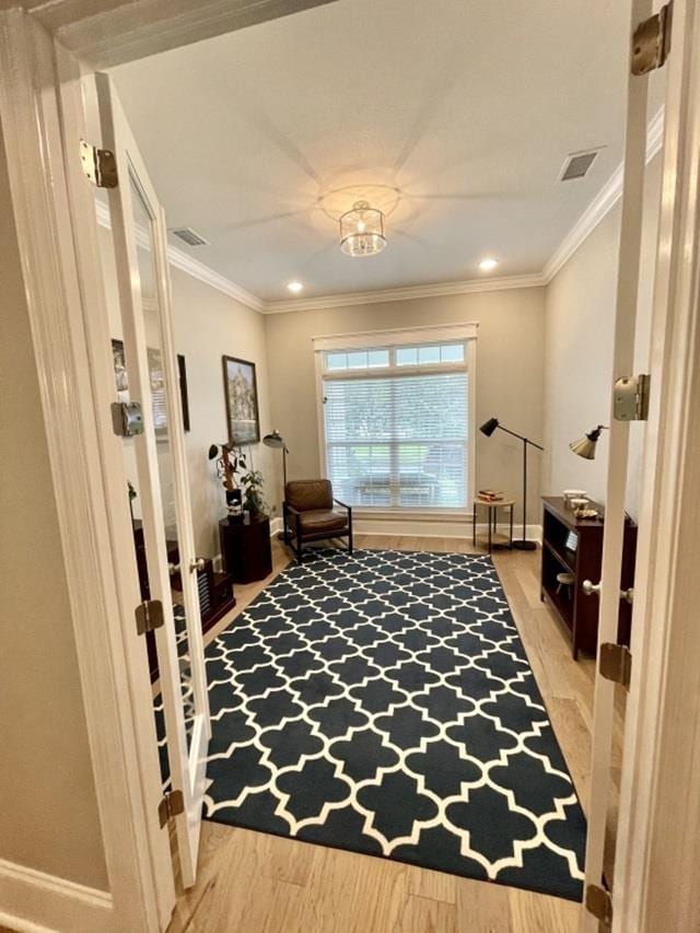 sitting room with crown molding and wood-type flooring