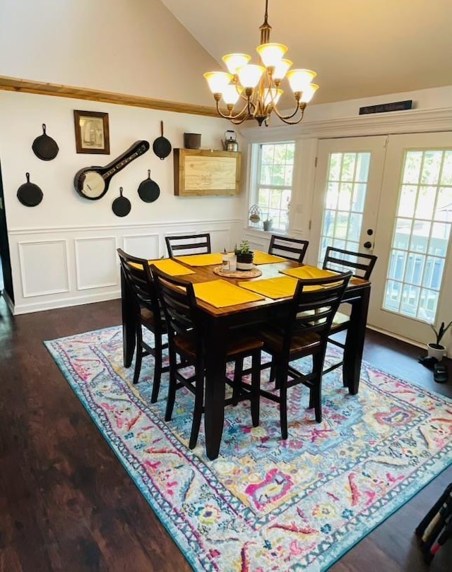 dining area featuring dark wood-type flooring, lofted ceiling, french doors, and an inviting chandelier