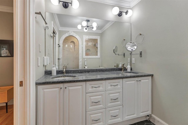 full bath with a tile shower, baseboards, crown molding, and a sink