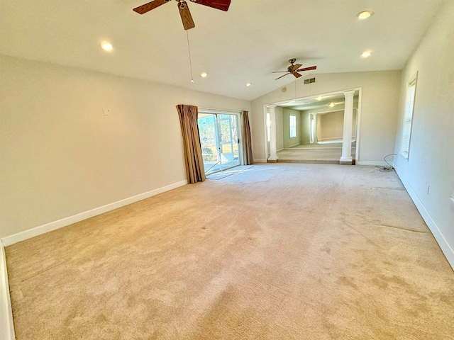 spare room featuring ornate columns, vaulted ceiling, light colored carpet, and ceiling fan