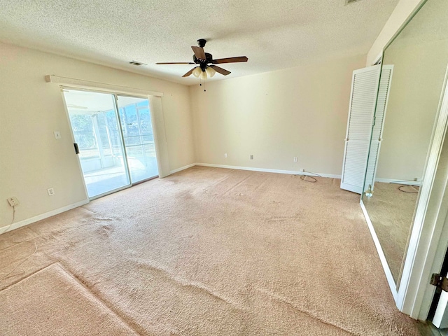 carpeted spare room with a textured ceiling and ceiling fan