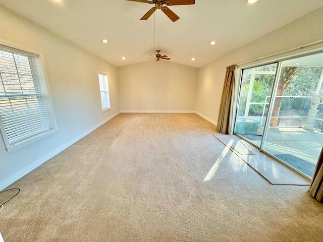 carpeted spare room featuring lofted ceiling, ceiling fan, and plenty of natural light