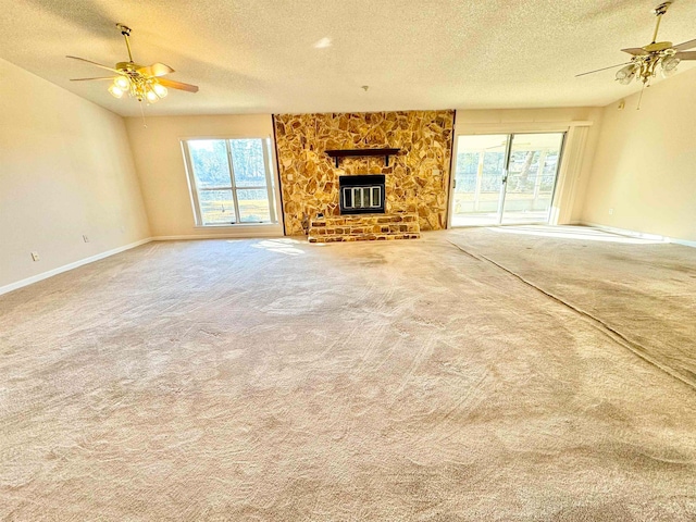 unfurnished living room with a fireplace, ceiling fan, a textured ceiling, and carpet