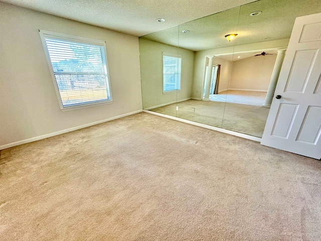 unfurnished bedroom featuring multiple windows, a textured ceiling, and carpet