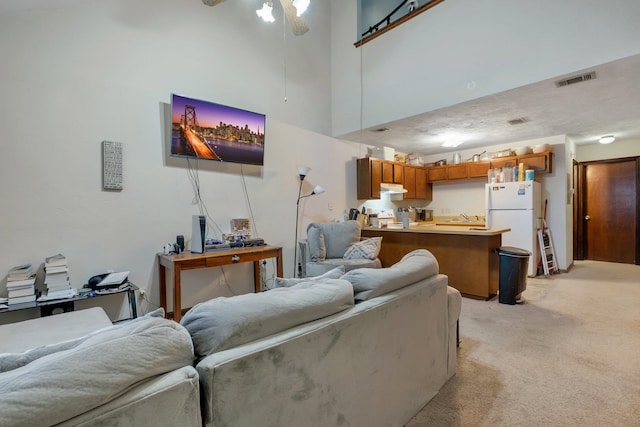 carpeted living room with sink, ceiling fan, and a towering ceiling