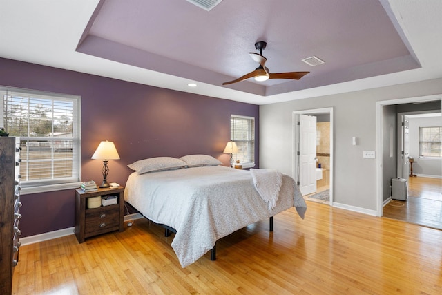 bedroom featuring ceiling fan, connected bathroom, and a raised ceiling