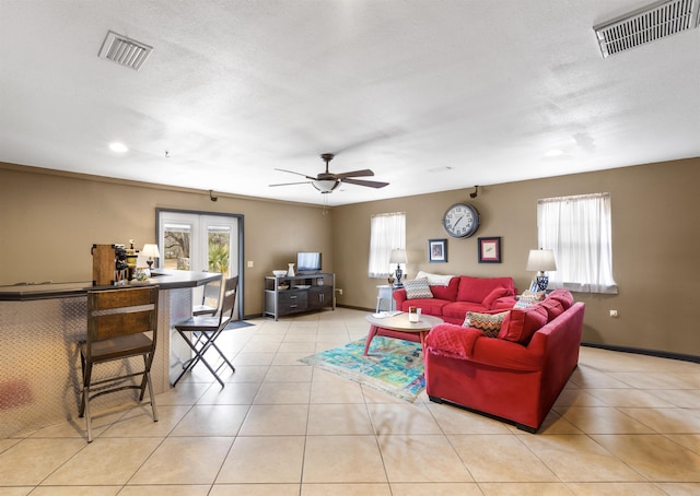 tiled living room with french doors, ceiling fan, and a textured ceiling