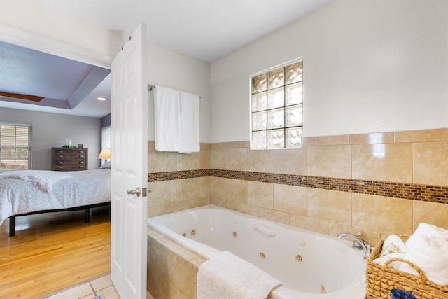 bathroom with a relaxing tiled tub, a wealth of natural light, and tile patterned floors