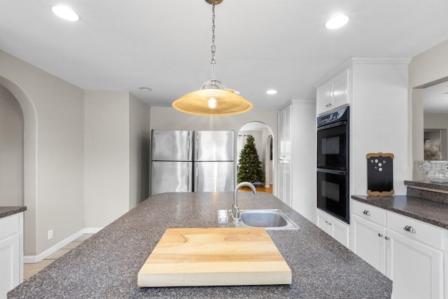 kitchen with sink, white cabinetry, stainless steel fridge, double oven, and pendant lighting