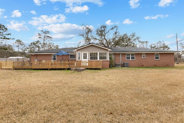 back of property with a deck, a lawn, and central air condition unit