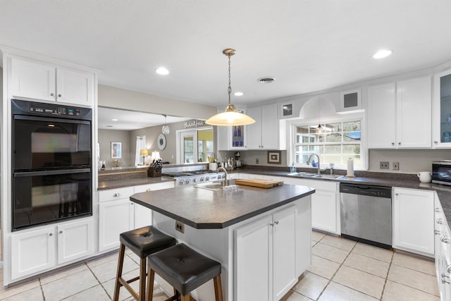 kitchen featuring sink, a breakfast bar area, double oven, an island with sink, and stainless steel dishwasher