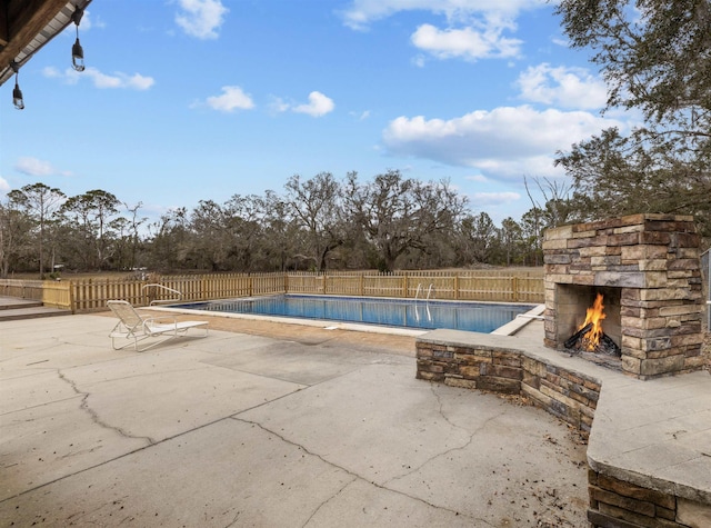 view of pool with an outdoor stone fireplace and a patio area