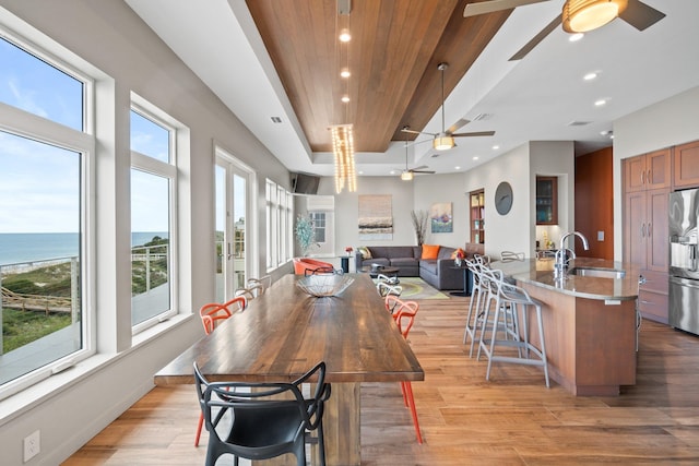 dining room with a wealth of natural light, a water view, and light hardwood / wood-style flooring