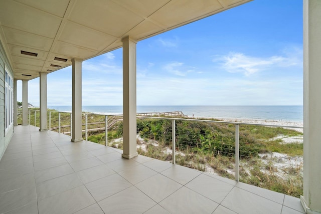 view of patio / terrace featuring a water view, a beach view, and a balcony