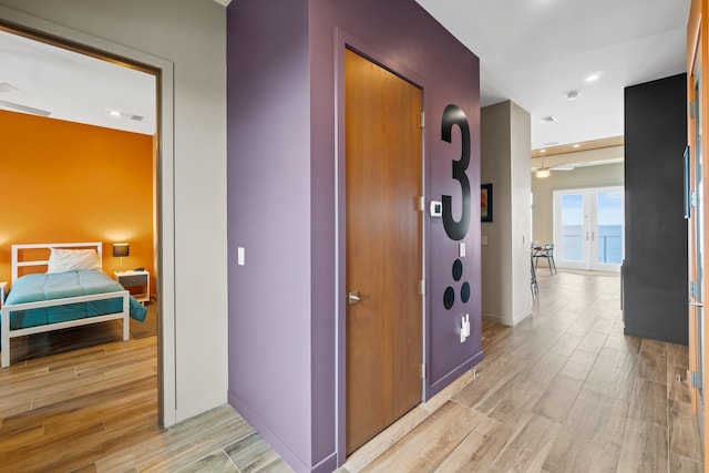 hall featuring a water view, light wood-type flooring, and french doors