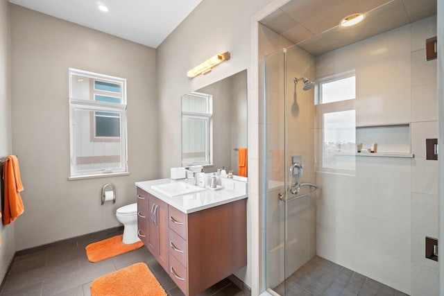 bathroom with toilet, vanity, a wealth of natural light, and a shower with shower door