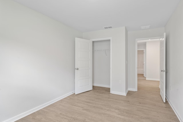 unfurnished bedroom with light wood-type flooring and a closet