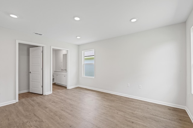 unfurnished bedroom with light wood-type flooring and ensuite bath